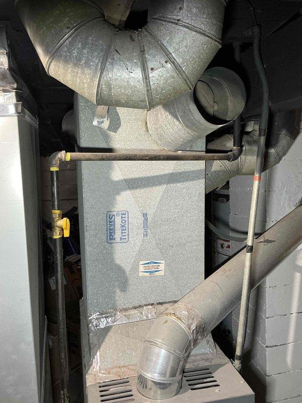 Conducted comprehensive assessment of non-functional air conditioning unit in basement mechanical room for complete system replacement estimate. Evaluated existing natural gas furnace installation, ductwork configuration, and gas line infrastructure with yellow-handled shutoff valve to determine equipment compatibility and replacement requirements. Documented current HVAC system layout including metal ductwork routing, structural clearances, and utility connections to provide accurate equipment sizing and installation specifications for new AC unit replacement.