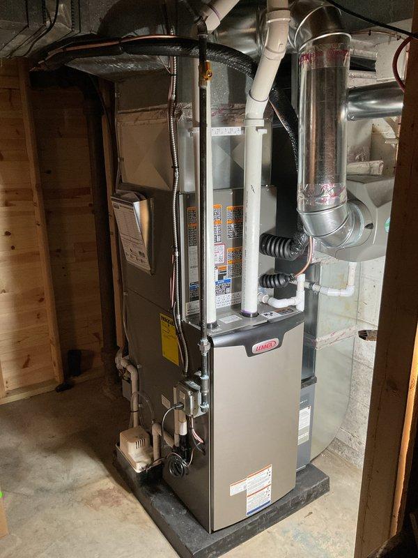 Completed installation of Lennox furnace and air conditioning system in residential basement location. Installed furnace on concrete pad with all necessary ductwork connections, including flexible metallic supply ducts, cylindrical metal distribution duct, and integrated humidifier system on ductwork. Connected white PVC condensate and vent piping, established electrical connections at main panel with dedicated circuits for A/C and furnace clearly labeled, and verified all mechanical and electrical systems operational. Air conditioning unit delivered to site pending final approval for side yard placement before exterior installation can be completed.