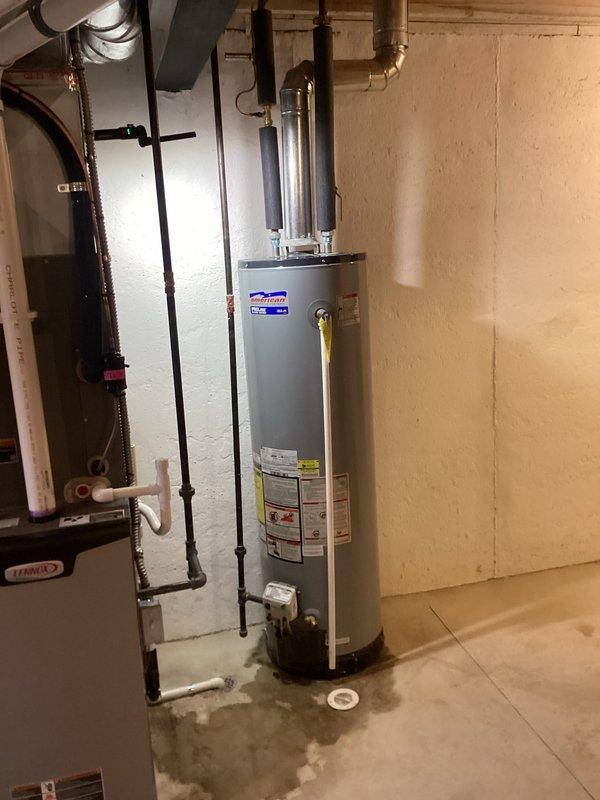 Responded to service call for leaking water heater in residential basement. Upon arrival, inspected 22-year-old American Water Heater Company ProLine Flame Guard tanked unit showing visible moisture and water staining on concrete floor around base. Confirmed active leak from aging tank, consistent with unit's age and expected service life in 24-25 year old home. Documented existing conditions with photographs showing water heater installation, adjacent HVAC system, venting configuration, and evidence of water accumulation near floor drain. Leak determined to be recent onset with no structural damage to surrounding area at time of inspection. Advised customer of findings and recommended tank replacement due to age and leak source.