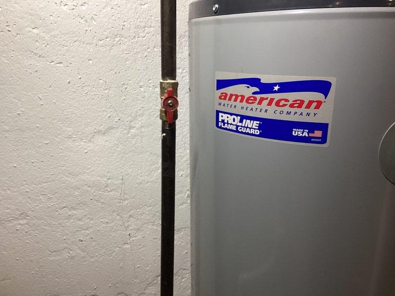 Responded to service call for leaking water heater in residential basement. Upon arrival, inspected 22-year-old American Water Heater Company ProLine Flame Guard tanked unit showing visible moisture and water staining on concrete floor around base. Confirmed active leak from aging tank, consistent with unit's age and expected service life in 24-25 year old home. Documented existing conditions with photographs showing water heater installation, adjacent HVAC system, venting configuration, and evidence of water accumulation near floor drain. Leak determined to be recent onset with no structural damage to surrounding area at time of inspection. Advised customer of findings and recommended tank replacement due to age and leak source.