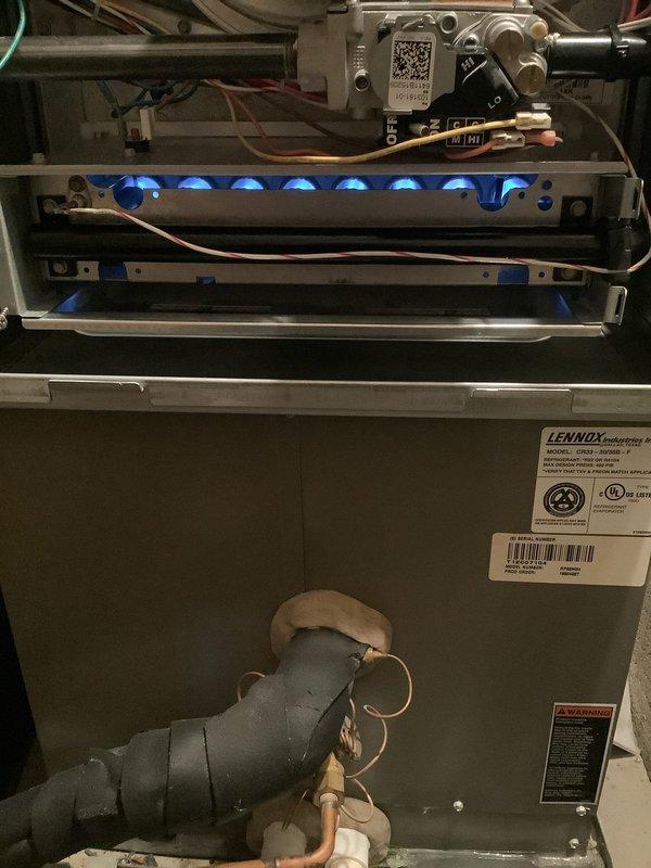 Completed annual heating maintenance on Lennox gas furnace system. Inspected burner assembly with unit operational, verified proper flame characteristics with blue flames present across all burners, checked gas valve and control module connections, and confirmed all safety labels and manufacturer documentation intact on unit housing.
