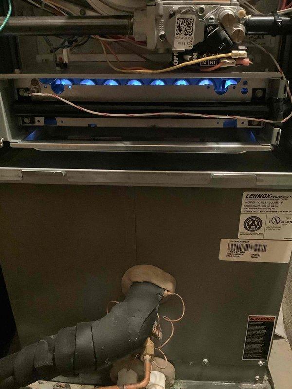 Completed annual heating maintenance on Lennox gas furnace system. Inspected burner assembly with unit operational, verified proper flame characteristics with blue flames present across all burners, checked gas valve and control module connections, and confirmed all safety labels and manufacturer documentation intact on unit housing.
