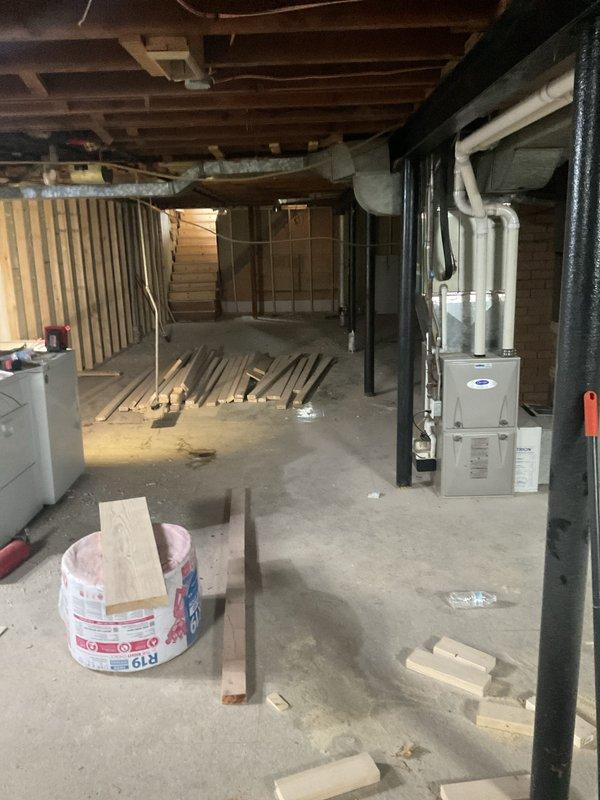 Conducted site visit to remeasure ductwork layout and assess requirements for furnace relocation and gas line modification in unfinished basement space. Documented existing HVAC equipment positioning, including current furnace unit with PVC venting and black ductwork configuration, as well as water heater location relative to proposed furnace placement. Evaluated structural elements including floor joists, support beams, and concrete columns to determine optimal routing for relocated gas line and revised ductwork system, ensuring compliance with clearance requirements and building codes.