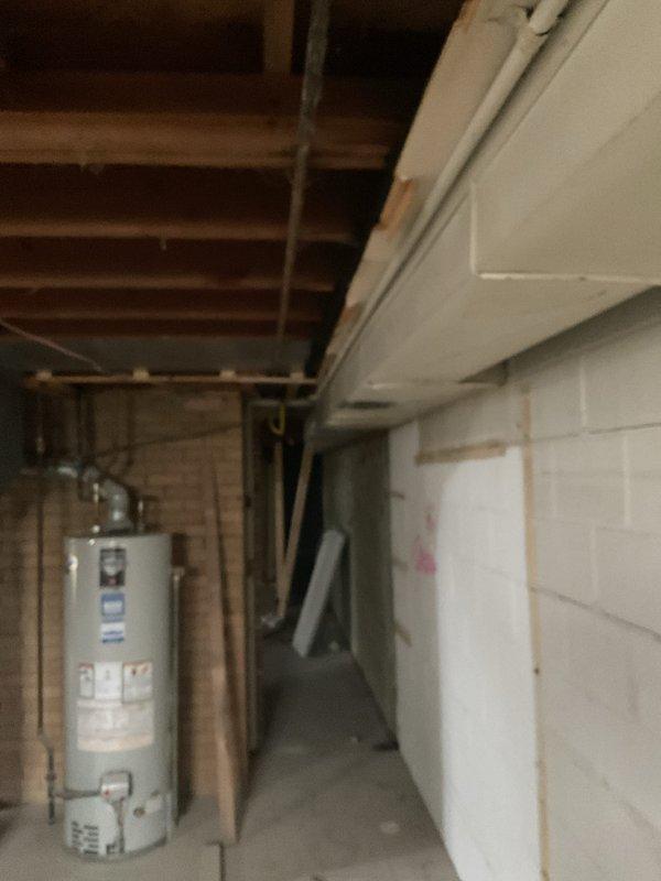 Conducted site visit to remeasure ductwork layout and assess requirements for furnace relocation and gas line modification in unfinished basement space. Documented existing HVAC equipment positioning, including current furnace unit with PVC venting and black ductwork configuration, as well as water heater location relative to proposed furnace placement. Evaluated structural elements including floor joists, support beams, and concrete columns to determine optimal routing for relocated gas line and revised ductwork system, ensuring compliance with clearance requirements and building codes.