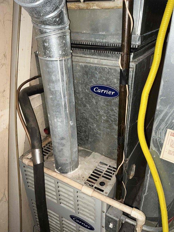 Conducted comprehensive evaluation of 26-year-old air conditioning system experiencing intermittent shutdown issues. Inspected existing Carrier furnace and AC installation in basement utility area, documenting extensive dust accumulation on ductwork, air handler components, and equipment surfaces. Assessed condition of flexible aluminum ductwork, gas line connections, and overall system infrastructure. Photographed existing HVAC configuration including main supply ducts, return air pathways, and equipment positioning for replacement planning purposes. Provided detailed estimate for complete AC system replacement due to age-related equipment failure and diminished reliability of current unit.