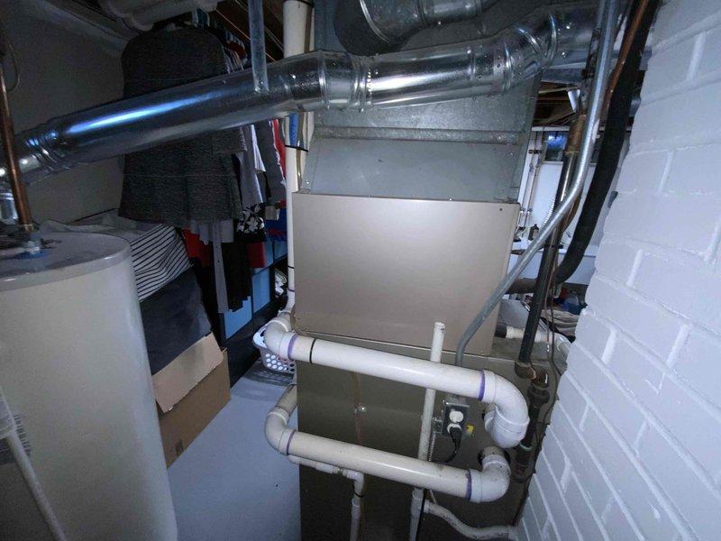 Conducted comprehensive assessment of inoperable 2010-2011 Bryant HVAC system in 750 square foot ranch home with full basement. Identified failed heat exchanger in 16-year-old Bryant furnace rendering unit unsafe for operation, along with aging air conditioning system of same vintage requiring replacement. Documented existing equipment configuration including air handler, ductwork, condensate pump assembly with PVC drainage system, and associated mechanical components. Photographed current installation showing metal ductwork distribution, copper refrigerant lines, electrical connections, and basement mechanical room layout to facilitate accurate full system replacement proposal for both heating and cooling equipment.