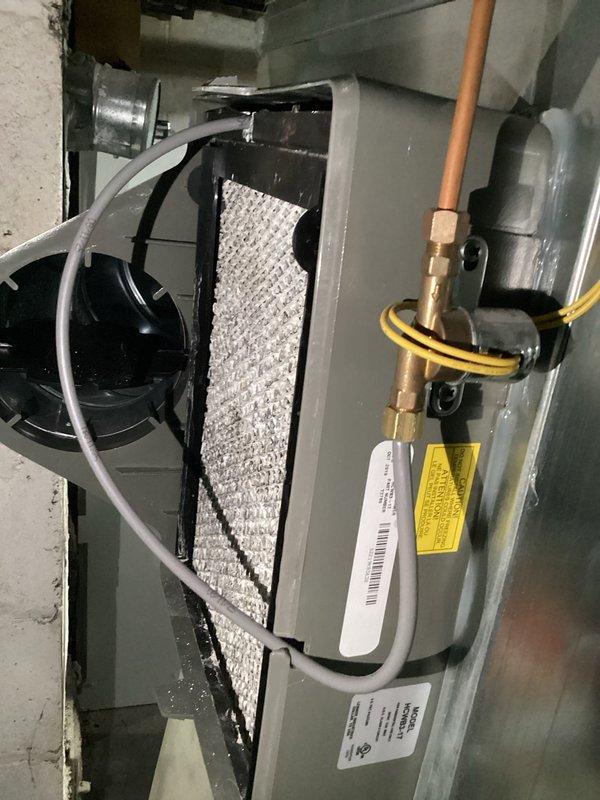 Responded to service call for leaking furnace-mounted humidifier on six-year-old HVAC system. Upon arrival, confirmed heating system was operating normally with no impact to primary function. Inspected humidifier unit and associated water supply lines, identifying source of leak at water feed connection. Documented equipment condition through photographs showing humidifier cabinet, internal components including distribution pad and water panel, and surrounding ductwork connections. Verified proper operation of blower motor and air handler components. Addressed leak issue and confirmed system integrity. Unit returned to normal operation with no further water discharge observed.