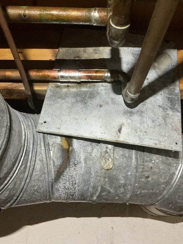 Responded to service call for humidifier leaking water. Upon inspection, found water staining on floor beneath humidifier installation connected to existing HVAC ductwork system. Assessed humidifier unit, associated plumbing connections, and water supply line for source of leak. Documented existing conditions with photographs showing copper piping, ductwork configuration, and evidence of water damage on concrete floor surface beneath unit.