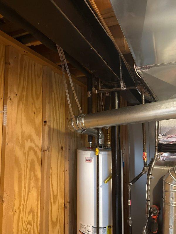 Completed installation callback to address code violation requiring proper B-vent support on 90,000 BTU furnace and 2-ton air conditioning system previously installed. Installed structural support bracket for B-vent ductwork per code requirements and documented corrected installation with photographs showing proper metal support hardware securing vent pipe to ceiling joists in mechanical room.