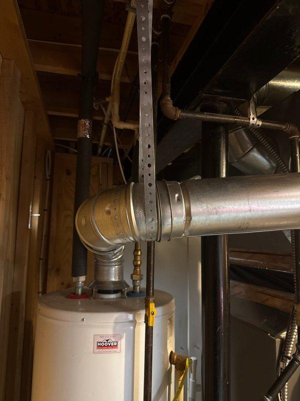 Completed installation callback to address code violation requiring proper B-vent support on 90,000 BTU furnace and 2-ton air conditioning system previously installed. Installed structural support bracket for B-vent ductwork per code requirements and documented corrected installation with photographs showing proper metal support hardware securing vent pipe to ceiling joists in mechanical room.