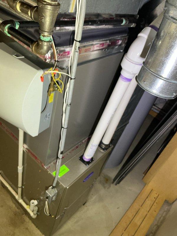 Performed routine preventative maintenance on residential central air conditioning system. Conducted comprehensive tune-up inspection including visual assessment of furnace unit, ductwork connections, condensate drainage system, and electrical control board components. Verified proper operation of all system controls and wiring connections. Adjusted air filter housing insertion point per customer request to improve accessibility. Confirmed unit warranty coverage status with customer. System operating within normal parameters with no deficiencies noted. Documented equipment condition through photographic records showing mechanical room installation and internal control panel assembly.