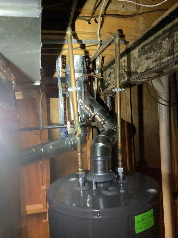 Completed HVAC install warranty inspection with focus on grounding and bonding recall verification. Documented water heater installation in basement utility area showing proper venting configuration with galvanized ductwork and associated piping connections. Inspected exterior electrical service panel, meter assembly, and conduit routing; noted existing rust staining on meter backing board requiring attention for proper system grounding integrity. Verified all mechanical connections, support structures, and electrical wiring pathways per manufacturer specifications and code requirements.