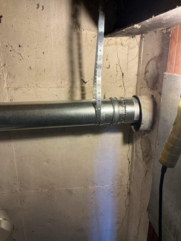 Responded to callback regarding possible chimney liner drop on recent HVAC installation. Upon inspection, verified proper installation and secure mounting of venting system through masonry wall penetration, confirmed all ductwork connections and support brackets are properly fastened and meeting code requirements. Documented current installation condition with photographs showing galvanized duct properly supported with metal strapping and wall-mounted structural supports, with no evidence of liner displacement or separation at chimney connection point.