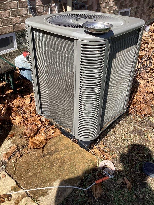 # HVAC Maintenance Summary

Completed scheduled ComfortGuard maintenance service on residential air conditioning system, performing comprehensive inspection and cleaning of outdoor condenser unit to ensure optimal cooling performance for the upcoming season.

# Work Performed

Performed preventive maintenance on outdoor air conditioning condenser unit positioned on concrete pad adjacent to brick structure. Conducted visual inspection of unit exterior, noting beige metal casing with vertical louvers in serviceable condition. Assessed fan grille and top-mounted components for proper mechanical integrity.

Cleared accumulated debris including dried leaves from perimeter of concrete pad and around base of condenser unit to ensure proper airflow and drainage. Removed organic material that had collected on and around equipment to prevent potential blockage of air intake passages.

Inspected electrical connections and conduit routing along adjacent wall structure. Verified secure mounting and