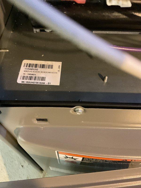 Completed full HVAC system installation including a Lennox 70,000 BTU furnace (model ML180UH070E36AK) and 2-ton air conditioning unit with rear discharge configuration. Installed all necessary ductwork with metallic silver curved supply runs extending from furnace cabinet, routed copper refrigerant lines along wall, and integrated Carrier auxiliary equipment into the system. Secured all mechanical and electrical connections, reconnected existing components to new system, and completed installation per permit requirements for mechanical and electrical work.