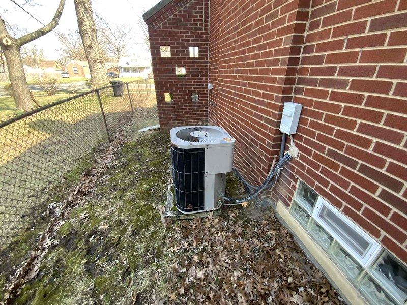 Provided estimate for replacement of non-functional outdoor air conditioning unit located at exterior corner of brick building. Existing AC condenser is inoperable and requires full replacement, while the 5-year-old furnace will remain in service. Assessment included evaluation of current refrigerant line set, electrical disconnect, and indoor air handler compatibility for new system installation.