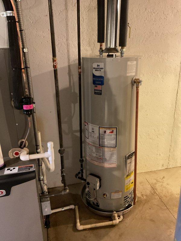 Installed a 40-gallon Bradford White tanked water heater in residential utility area with proper copper supply line connections, PEX piping integration, and code-compliant venting. Added drip pan beneath unit for leak protection and safety compliance. Reconnected all water supply lines, installed shut-off valves, and verified proper operation of the system upon completion.
