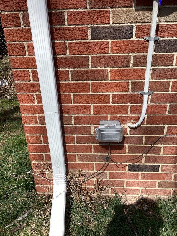 Completed full HVAC system installation including 70,000 BTU furnace and 2.5 ton air conditioning unit positioned on right side of property. Installed new condensate drain lines with PVC piping mounted to exterior brick wall with proper bracketing, connected to existing gutter system. Mounted gray electrical disconnect box on exterior wall with appropriate conduit and wiring. Positioned furnace unit in basement on platform with all necessary ductwork connections, copper refrigerant lines, and white PVC venting routed through walls. Installed electrical components including wall-mounted junction boxes and conduit runs. Reconnected all existing systems to new equipment. Obtained mechanical and electrical permits prior to installation. All equipment tested and operational upon completion.