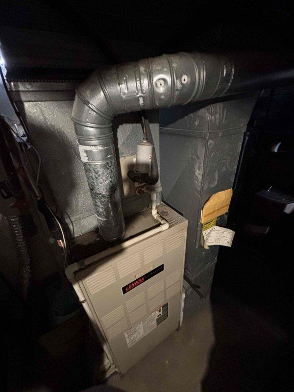 Conducted comprehensive assessment of existing HVAC system in basement utility area for full system replacement estimate. Evaluated current furnace unit with beige corrugated front panel and existing metallic ductwork configuration, including flexible and rigid duct connections. Documented equipment condition, installation layout, and spatial constraints in utility area shared with water heater and storage. Photographed existing system components and mechanical room setup to provide detailed replacement recommendations for both furnace and central air conditioning units, as customer requested immediate system replacement timeline.