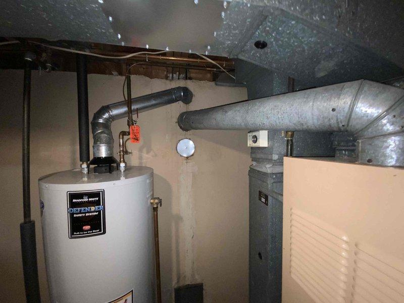 Completed on-site assessment for replacement estimate of existing basement-installed heating and cooling system serving medium-sized residential space of 1200-2000 square feet. Evaluated current natural gas furnace and associated ductwork configuration, documented equipment specifications, and photographed installation layout including existing water heater proximity and electrical panel location. Provided comprehensive replacement options for complete furnace and air conditioning system upgrade.