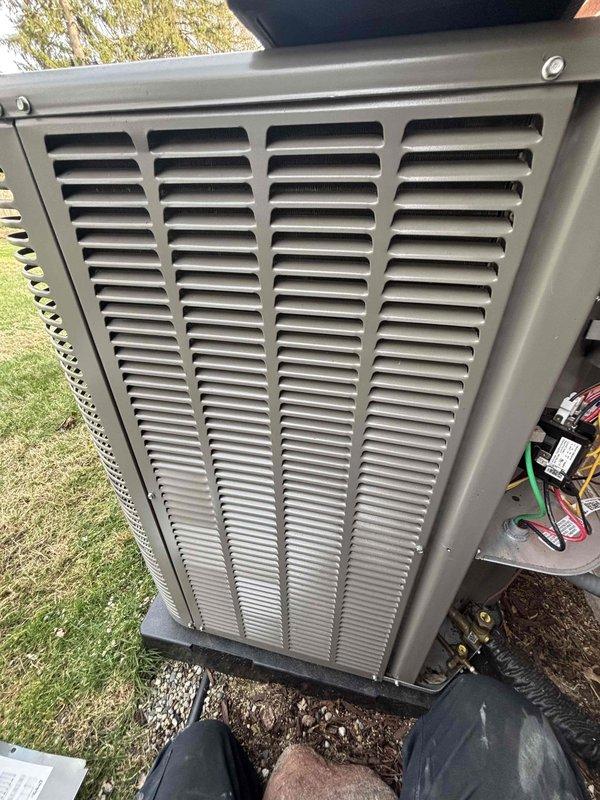 Performed comprehensive AC tune-up and furnace maintenance on 14-month-old forced air system. Conducted full system diagnostics on outdoor condensing unit, including refrigerant pressure testing with manifold gauges to verify proper charge levels and system performance. Inspected condenser coil through louver grille, confirmed adequate airflow, and verified unit operation on concrete pad with proper drainage. Both heating and cooling systems found operating within manufacturer specifications with no deficiencies noted.