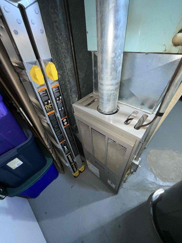 Conducted comprehensive assessment of aging 1993 natural gas furnace and air conditioning system located in basement for replacement estimate. Current equipment operational but nearing end of serviceable life at 33 years old. Evaluated existing HVAC installation, ductwork configuration, and mechanical room layout. Documented equipment specifications, clearances, and noted moisture staining on concrete floor near water heater, which may require attention during installation. Provided recommendations for complete furnace and air conditioning system replacement with modern high-efficiency equipment.