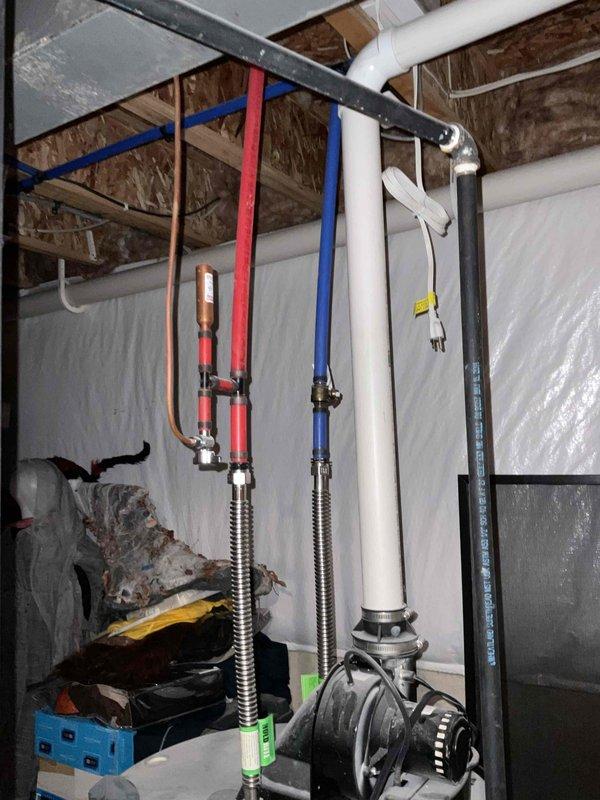 Responded to water heater leak in basement utility area. Inspected white cylindrical tank water heater with multiple supply line connections, confirming active leak condition. Documented existing plumbing configuration including hot and cold water lines, pressure relief valve assembly, and top-mounted circulation pump. Photographed unit condition, piping connections, and surrounding mechanical systems to provide comprehensive estimate for water heater replacement. Customer previously had HVAC system installed in 2015.