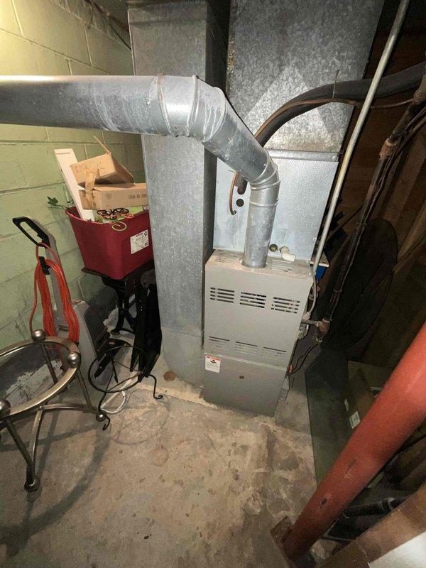Conducted comprehensive assessment of non-operational HVAC system with equipment exceeding 10 years of service life. Evaluated basement-installed natural gas furnace with existing ductwork configuration and exterior air conditioning unit positioned on lava rock landscaping. Documented current system conditions including furnace cabinet, supply and return ductwork connections, and outdoor condensing unit placement to provide replacement equipment recommendations and installation specifications.