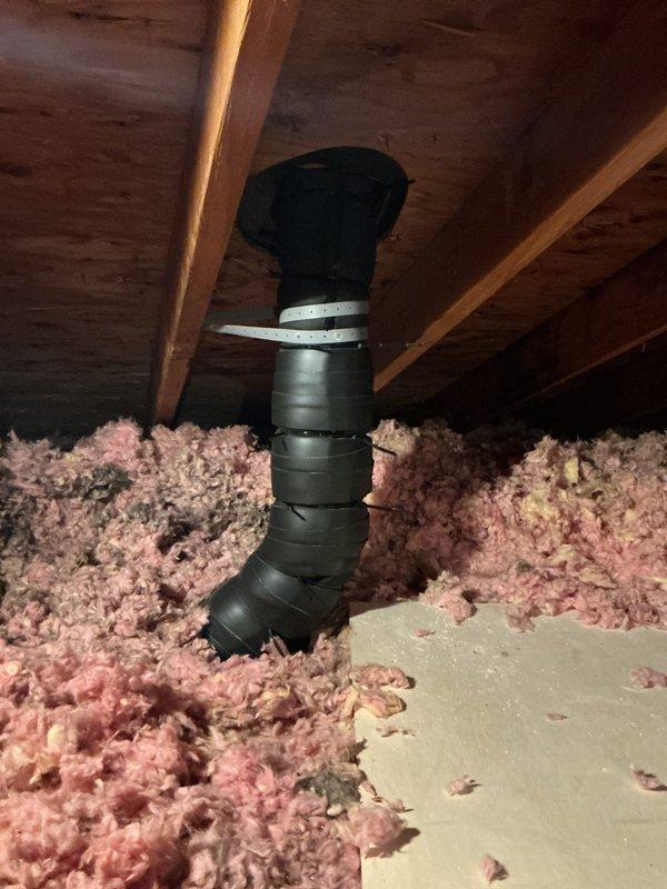 Responded to callback for post-installation issues on 110,000 BTU furnace and 4-ton AC system. Accessed attic space to inspect exhaust vent pipe reported as crooked and potentially unstable on roof penetration. Upon inspection, found flexible exhaust duct secured with metallic foil tape running vertically through attic insulation to roof exit point. Assessed structural integrity and mounting of exhaust termination. Additionally investigated booster fan malfunction reported as continuously running since original installation. Documented attic conditions showing loose-fill fiberglass insulation and ductwork routing for warranty and quality assurance purposes.