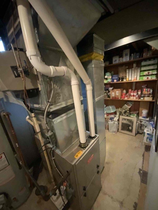 Conducted air conditioner replacement estimate for 25-year-old residential cooling system in basement mechanical room. Assessed existing Bryant furnace installation, evaluated current PVC venting configuration, and documented equipment layout including adjacent water heater and storage areas. Photographed mechanical systems and discussed replacement timeline with homeowner, who requested installation completion within 30 days.