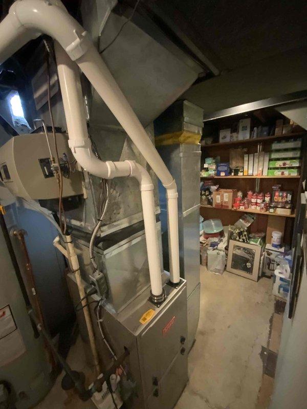 Conducted air conditioner replacement estimate for 25-year-old residential cooling system in basement mechanical room. Assessed existing Bryant furnace installation, evaluated current PVC venting configuration, and documented equipment layout including adjacent water heater and storage areas. Photographed mechanical systems and discussed replacement timeline with homeowner, who requested installation completion within 30 days.