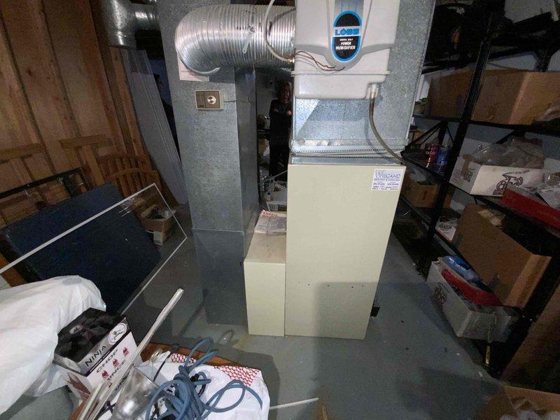 Completed full system estimate for HVAC replacement at residential property. Existing 30+ year old furnace with cracked heat exchanger and air handler unit located in basement utility area requires replacement due to safety concerns and end of serviceable life. Documented current indoor equipment configuration including wall-mounted air handler with flexible ductwork and aging furnace cabinet, as well as outdoor condenser unit positioned on concrete pad against brick exterior wall. Provided comprehensive replacement options for complete heating and cooling system to address immediate safety hazard and restore reliable climate control.