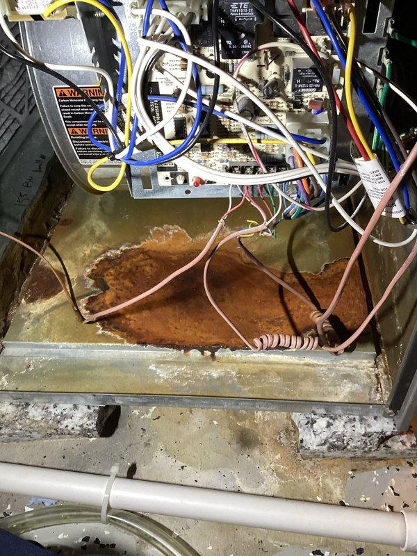 Completed annual cooling maintenance on residential split system. Inspected outdoor condensing unit, confirmed proper operation of compressor and condenser fan motor. Checked refrigerant levels and electrical connections at outdoor unit. Indoor air handler inspection revealed significant rust corrosion and standing water in drain pan, indicating chronic condensate drainage issues. Documented excessive moisture damage to metal components and mineral deposit buildup. Control board and electrical connections inspected and found operational despite moisture exposure in cabinet. Recommended immediate attention to drainage system and potential drain pan replacement to prevent further deterioration and possible water damage to structure.