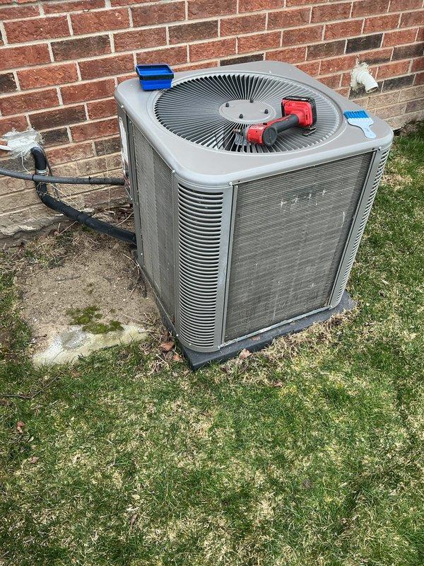 Completed routine air conditioning maintenance on residential outdoor condenser unit. Performed comprehensive AC tune-up including visual inspection of unit exterior, cabinet, and fan grille assembly. Connected manifold gauges to service ports and verified refrigerant pressures and system charge levels. Inspected electrical disconnect, conduit connections, and refrigerant line sets along brick wall mounting. Evaluated condenser coil condition through louvers, noting normal outdoor weathering and minor surface accumulation. Confirmed fan motor operation and proper airflow through top-mounted grille. Tested system performance and verified unit operating within manufacturer specifications. All components functioning properly with no deficiencies noted requiring immediate attention.