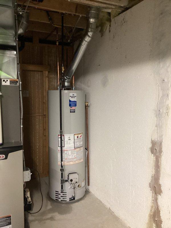 Completed installation of 40-gallon tanked water heater in residential basement utility area. Unit was properly positioned and secured against concrete wall with all necessary plumbing connections made, including hot and cold water supply lines. Metallic exhaust vent pipe was installed and routed upward through ceiling structure with proper elbow configuration to ensure safe ventilation of combustion gases. All connections were tested for proper operation and leak-free performance. Installation was completed in accordance with applicable building codes, and required permits were obtained prior to work commencement.