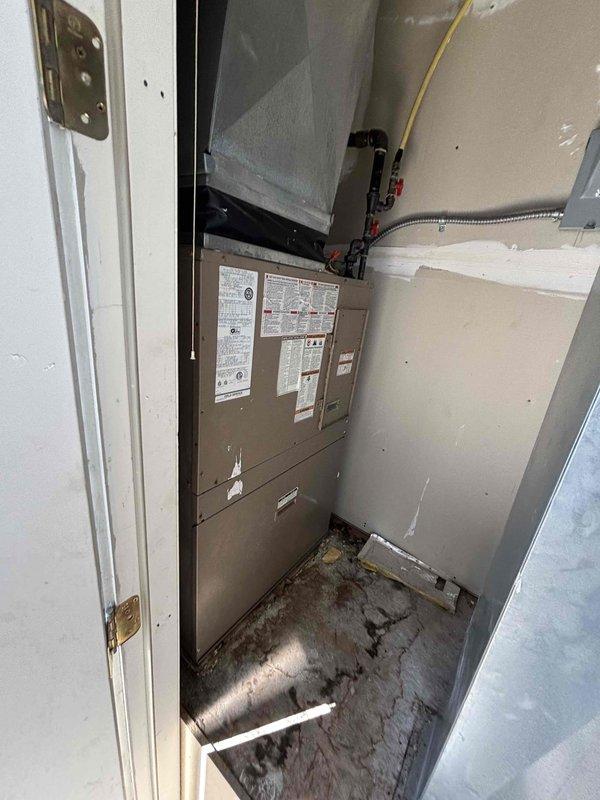 Conducted site evaluation for replacement of combo packaged HVAC unit in apartment setting. Assessed existing equipment housed in dedicated utility closet, documented electrical panel configuration with approximately 16-20 circuit breakers, and inspected current furnace/air handler installation with connected ductwork and plenum. Noted significant floor staining and water damage around base of existing unit indicating previous moisture intrusion issues that will require remediation during replacement process.