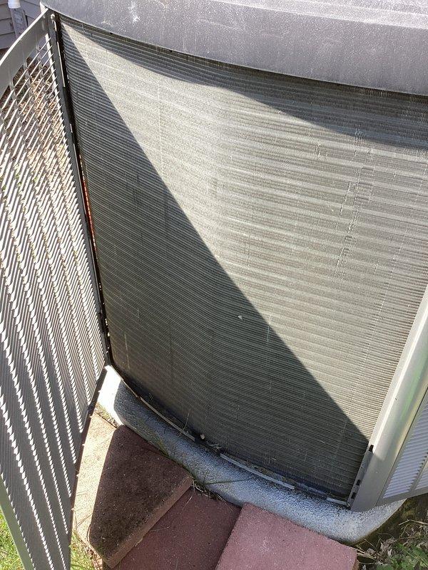 Completed annual preventive maintenance on residential split system air conditioning unit. Performed comprehensive inspection of outdoor condenser unit, noting diagonal discoloration pattern on heat exchanger coils indicating differential dirt accumulation and environmental exposure. Verified unit operational status, checked electrical connections, and confirmed proper mounting on concrete pad. System found to be in functional condition with no immediate service requirements identified during this scheduled maintenance visit.