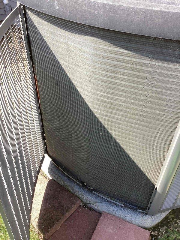 Completed annual preventive maintenance on residential split system air conditioning unit. Performed comprehensive inspection of outdoor condenser unit, noting diagonal discoloration pattern on heat exchanger coils indicating differential dirt accumulation and environmental exposure. Verified unit operational status, checked electrical connections, and confirmed proper mounting on concrete pad. System found to be in functional condition with no immediate service requirements identified during this scheduled maintenance visit.