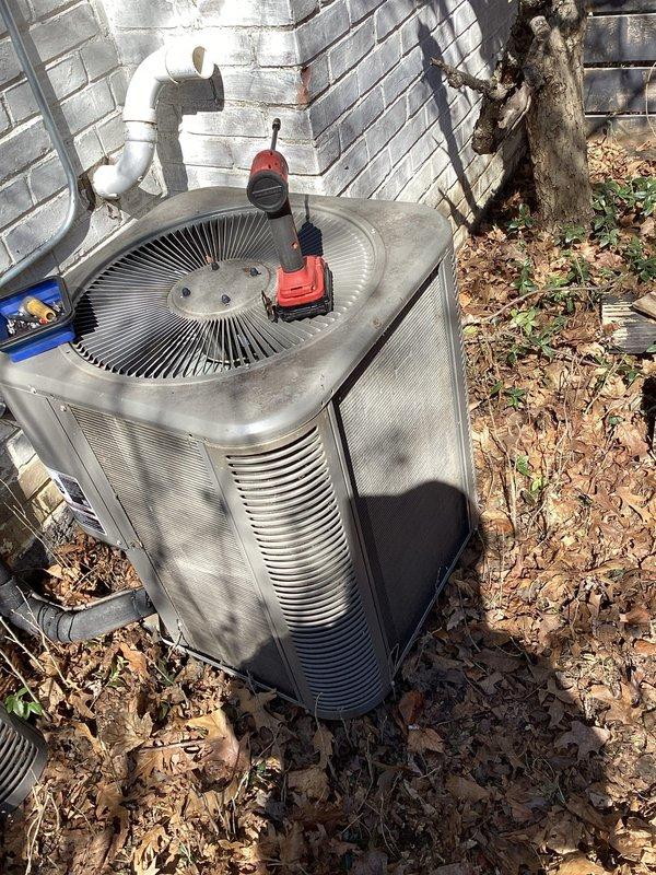 Completed comprehensive ComfortGuard maintenance package on outdoor HVAC condenser unit. Cleared significant accumulation of dried leaves and organic debris from around unit and confined space between equipment and building wall to restore proper airflow and prevent potential system efficiency issues. Performed standard maintenance inspection and service procedures on the air conditioning system.