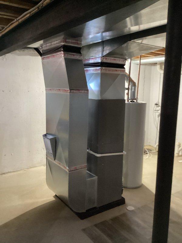 Completed full HVAC system installation including a 70,000 BTU furnace and 2.5 ton air conditioning unit in basement utility area. Installed custom-fabricated sheet metal ductwork system with multiple rectangular transitions extending from floor to ceiling joists. Ran new dedicated electrical circuit to support equipment. Secured all necessary mechanical and electrical permits prior to installation. Routed PVC condensate drainage with proper wall mounting and brackets. All equipment installed per manufacturer specifications and local code requirements, with system tested and operational upon completion.