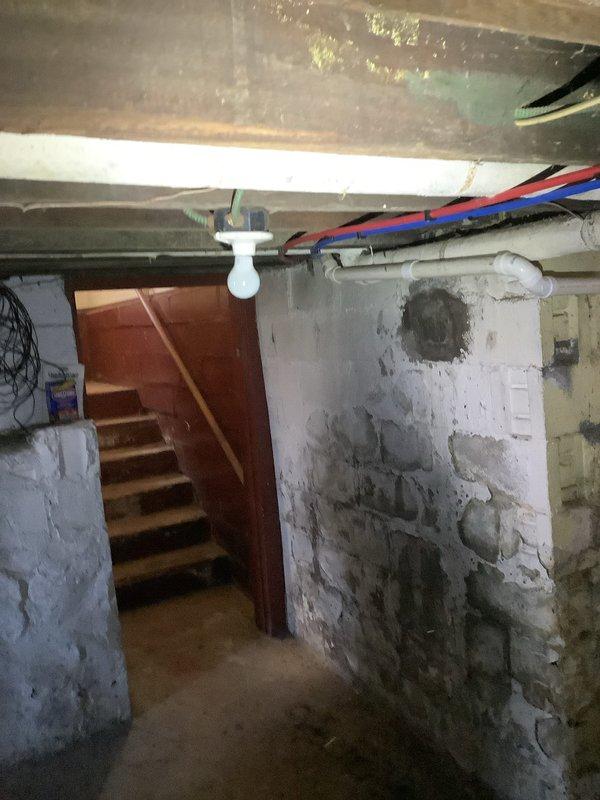 Completed comprehensive whole home electrical inspection. Documented electrical panel condition, noting corrosion debris accumulation at bottom of enclosure requiring attention. Assessed basement electrical infrastructure including exposed wiring, conduit routing, and overall system integrity in moisture-prone environment with evidence of water intrusion on surrounding masonry surfaces.