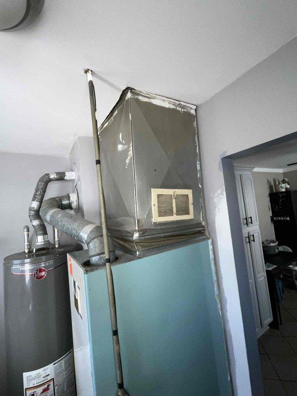 Conducted on-site assessment for complete HVAC system replacement in residential property. Evaluated existing aging furnace unit located in interior utility closet, which was determined to be incompatible with central air conditioning integration due to system age and design limitations. Documented current equipment configuration including vertical air handler setup with adjacent water heater installation and existing ductwork routing. Photographed mechanical room layout, equipment specifications, and spatial constraints to prepare comprehensive replacement estimate for new furnace and central air conditioning system installation.