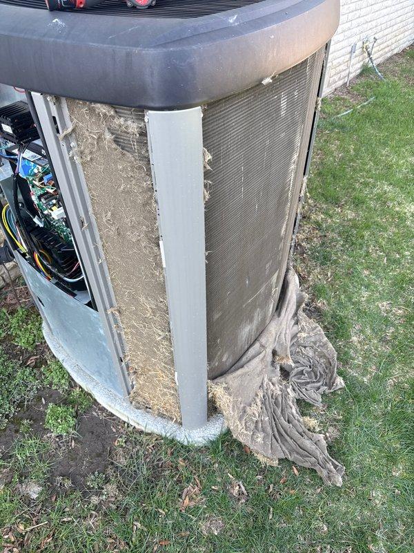 Completed annual cooling maintenance on residential outdoor condensing unit. Removed and inspected access panels, revealing heavily soiled air filter with significant dirt and debris accumulation. Cleaned filter screen, inspected electrical connections and wiring for proper operation, verified refrigerant lines and internal components. Unit restored to operational condition with all panels secured and system tested for proper function.