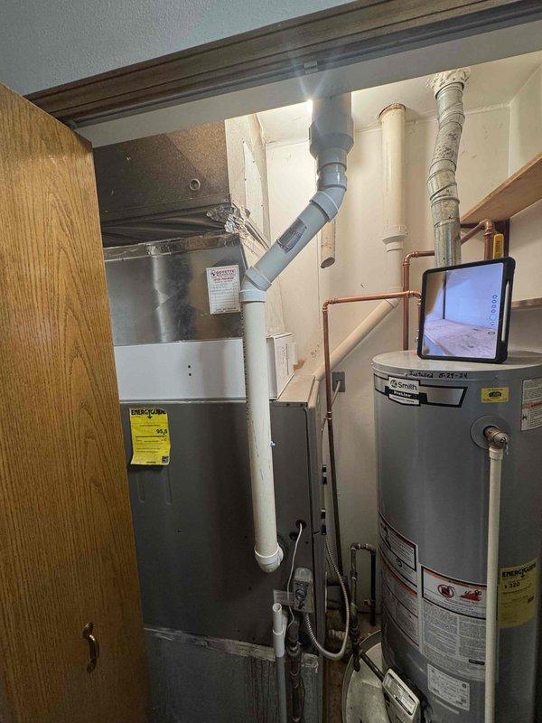 Conducted comprehensive full system replacement estimate for a medium-sized residential property (1200-2000 sq ft) with existing 15-year-old natural gas furnace and 16-year-old air conditioning system located in utility closet. Assessed current gray metal furnace unit with PVC venting, evaluated ductwork configuration, and inspected electrical connections and gas line accessibility. Documented equipment placement constraints in mechanical room shared with water heater, photographed existing installation including copper refrigerant lines and condensate drainage setup. Provided replacement options for combined heating and cooling system utilizing natural gas energy source, discussed crawlspace unit placement considerations, and reviewed available financing solutions for complete HVAC system upgrade to improve efficiency and reliability for homeowner seeking replacement within current season.