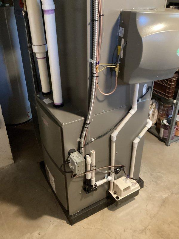 Completed full HVAC system installation including a 90,000 BTU furnace and 3-ton air conditioning unit in basement location. Installation included proper refrigerant line routing with copper piping, white PVC condensate drainage system, venting configuration, humidifier integration, and reconnection of all necessary utilities. All equipment mounted on appropriate base pad, permits obtained, mechanical components properly secured, and system tested for operational functionality per manufacturer specifications.