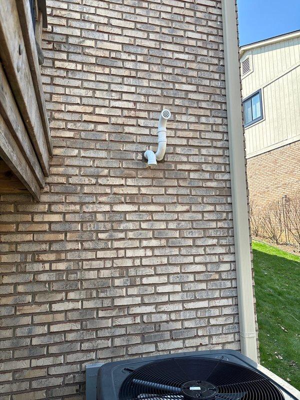 Completed full installation of Energy Star certified tankless water heater in basement mechanical room, mounted to concrete block wall with proper structural support. Installed new copper supply piping with inverted U-configuration, routed black electrical conduit and wiring for dedicated circuit, and connected white PVC exhaust/intake venting system through exterior brick wall with appropriate termination fittings and mounting brackets. All mechanical and electrical permits obtained prior to installation, ensuring code-compliant setup with organized pipe routing and professional finish.