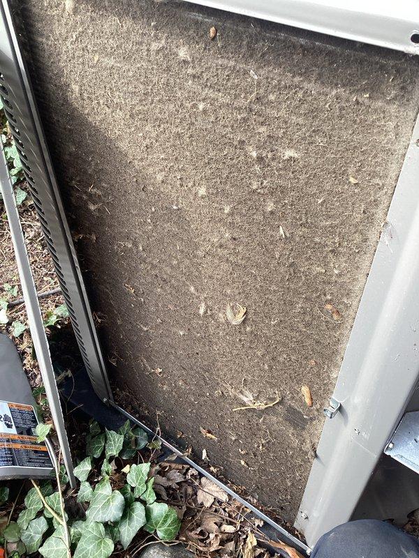 Completed routine Air Care Maintenance on residential air conditioning system. Found air filter heavily saturated with dust, dirt, and organic debris including leaves and twigs, causing significant airflow restriction. Inspected condenser coil and identified substantial accumulation of dirt, dust, and environmental contaminants across fin surfaces, with concentrated buildup in middle and lower sections reducing heat transfer efficiency. Documented equipment condition with photos showing both filter and coil contamination levels prior to service completion.
