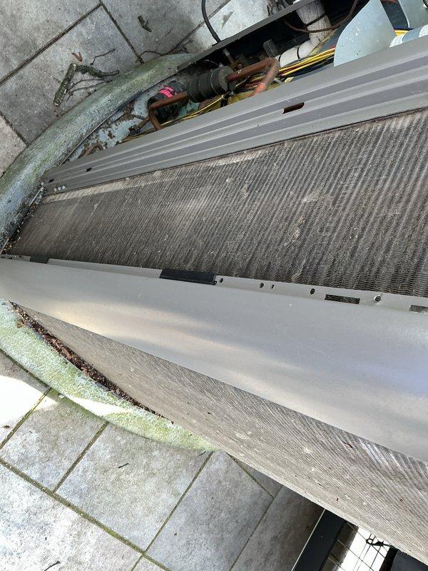 Completed annual cooling maintenance on outdoor HVAC system. Inspected evaporator coils, heat exchanger fins, copper refrigerant lines, and condenser unit, noting accumulation of dirt and debris on corrugated metal surfaces and oxidation on copper piping from weather exposure. Unit operational with normal signs of outdoor weathering; concrete pad showed algae growth and debris requiring routine cleanup.