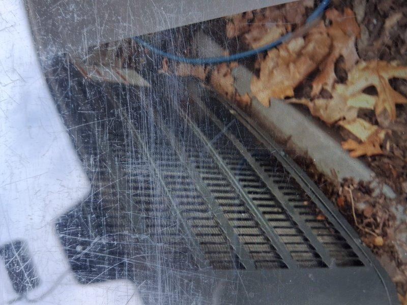 Completed scheduled maintenance on air conditioning system. Inspected evaporator coil through access panel, noting significant surface wear on return air grate and rust-colored staining present in drain pan area, indicating potential condensate drainage concerns. Documented equipment condition with photos showing triangular A-coil configuration with visible fin deterioration and debris accumulation at outdoor air intake requiring attention during next service interval.