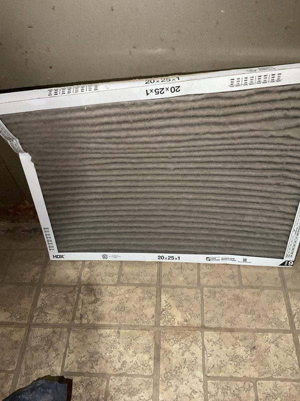 Responded to no heat call on residential furnace system. Upon arrival, homeowner reported unit alternating between hot and cold air output and requiring thermostat to be set significantly higher than normal to maintain adequate heating. Conducted visual inspection of furnace and surrounding utility area, noting aged equipment and deteriorated conditions in mechanical room with visible ceiling damage and worn surfaces.

Performed system diagnostics and discovered severely restricted airflow due to heavily soiled air filter. Removed 20x25x1 HDX filter which exhibited extensive dust and particulate accumulation throughout pleated media, causing reduced system efficiency and improper cycling. Dirty filter was restricting airflow to heat exchanger, resulting in temperature fluctuations and inadequate heat distribution. This restriction forced system to run extended cycles and prevented proper heat transfer, explaining why thermostat required higher settings to achieve desired temperatures.
